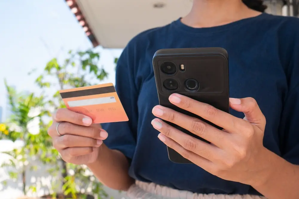 Close-up of a consumer holding a Credit One credit card and smartphone amid robocall lawsuit updates